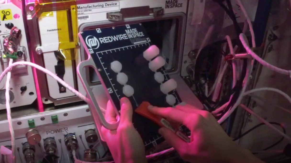Caption: An astronaut removes a recent AstroRad subunit from an AMF printing plate. (Credit: Redwire)